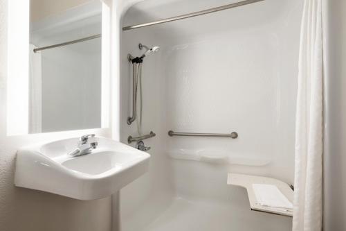 a white bathroom with a sink and a shower at Candlewood Suites Watertown Fort Drum by IHG in Evans Mills