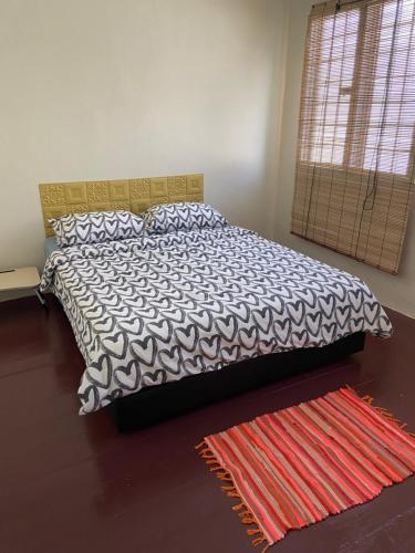 a bedroom with a bed with a black and white comforter at JAVA 6 HOME 5 min to Jonker in Melaka