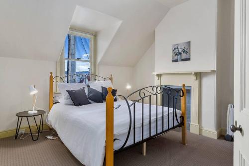 ein Schlafzimmer mit einem großen Bett mit weißer Bettwäsche und einem Fenster in der Unterkunft Cosy Glebe cottage - walk to central Hobart in Hobart