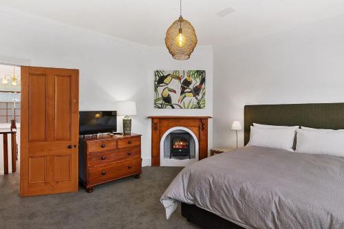 a bedroom with a bed and a fireplace and a television at Fabulous 2 level city pad in historic building in Hobart
