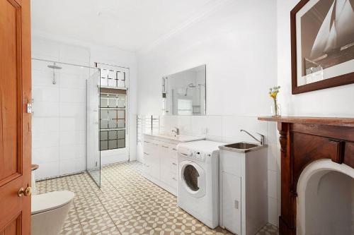 uma casa de banho branca com uma máquina de lavar roupa e um lavatório em Fabulous 2 level city pad in historic building em Hobart