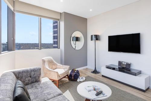 a living room with a couch and a tv at Meriton Suites Church Street, Parramatta in Sydney