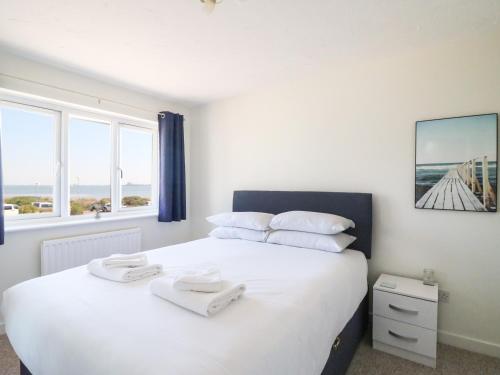 1 dormitorio con 1 cama grande con sábanas y almohadas blancas en Tidal Drift en Weymouth