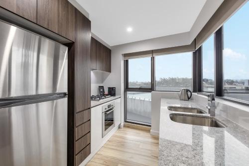 a kitchen with a sink and a counter with windows at Meriton Suites Church Street, Parramatta in Sydney