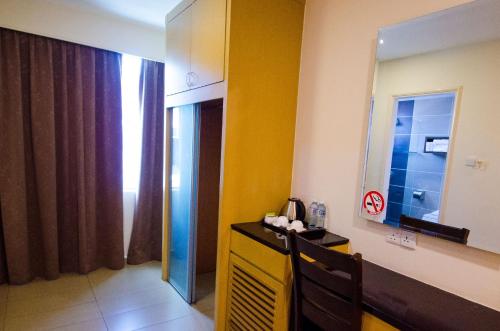 Habitación con pared amarilla y espejo. en GRAND EASTERN HOTEL SDN BHD en Kota Kinabalu