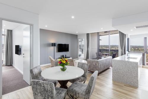a living room with a table and chairs at Meriton Suites Church Street, Parramatta in Sydney