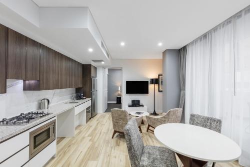 cocina y sala de estar con mesa y sillas en Meriton Suites Church Street, Parramatta, en Sídney