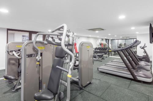 a gym with treadmills and machines in a room at Meriton Suites Church Street, Parramatta in Sydney
