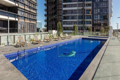 a swimming pool with chairs and a fish in the water at Meriton Suites Church Street, Parramatta in Sydney