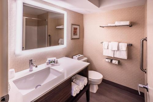 a bathroom with a sink and a toilet and a mirror at Holiday Inn Hotel & Suites Osoyoos, an IHG Hotel in Osoyoos