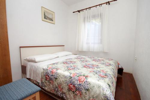 a bedroom with a bed with a floral comforter and a window at Seaside secluded apartments Cove Skozanje, Hvar - 4024 in Gdinj