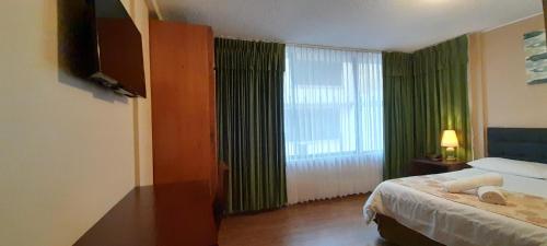 a hotel room with a bed and a large window at Hodu Hospedaje in Quito