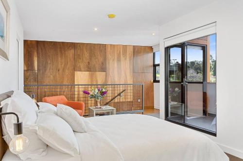 - une chambre avec un lit blanc et une chaise orange dans l'établissement Stunning Warehouse Pad - Moments from the Waterfront, à Hobart