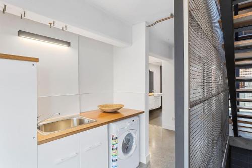 une cuisine blanche avec un évier et une machine à laver dans l'établissement Stunning Warehouse Pad - Moments from the Waterfront, à Hobart