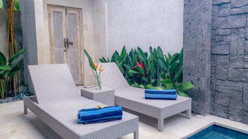 twee stoelen met blauwe kussens op een patio bij Vinna Villa Seminyak by The Wina Resorts in Kerobokan