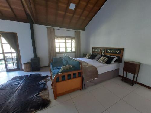 a bedroom with a bed and a couch in it at Lumiar Eco Lodge - Chalé Pedra Riscada in Nova Friburgo