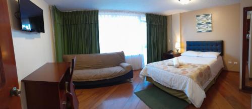 a bedroom with a bed and a couch and a window at Hodu Hospedaje in Quito