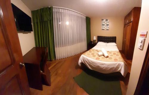 a small bedroom with a bed and a television at Hodu Hospedaje in Quito