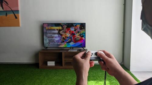 a person holding a video game controller in front of a television at OA HOTEL Wushih Marina in Toucheng