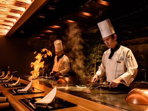 two chefs standing in a kitchen preparing food at Hotel Flags Kuju Kusima in Sasebo