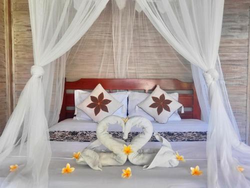 two swans made into hearts are on a bed at Vista Huts Lembongan in Nusa Lembongan