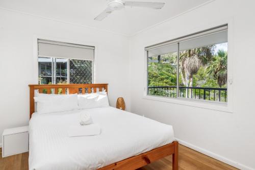 a bedroom with a bed and two windows at Wategos Surf Shack in Byron Bay