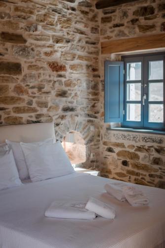 a bedroom with a white bed with a stone wall at Alika Resort in Álika