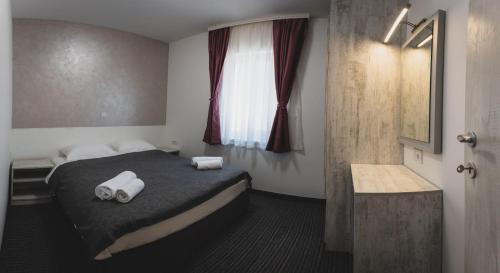 a bedroom with a bed with two towels on it at Navigator in Palić
