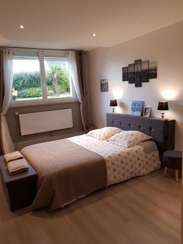 une chambre avec un grand lit et une fenêtre dans l'établissement La Poterie, à Étretat