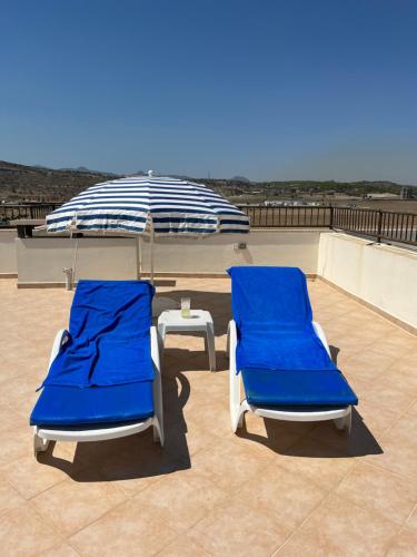 two blue chairs and an umbrella on a roof at Seaview apartment with roof terrace in Kalecik