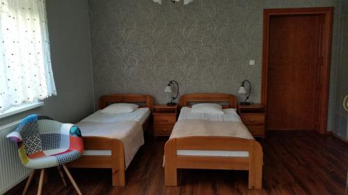 Cette chambre comprend 2 lits et une chaise. dans l'établissement Villa Lena, à Gdańsk