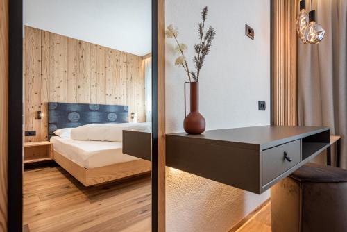a bedroom with a bed and a table with a vase on it at Deluxe Appartement Arve in Valdaora