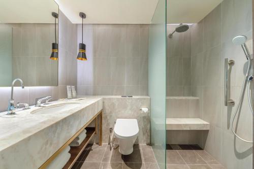 a bathroom with a shower and a toilet and a sink at PARKROYAL on Beach Road, Singapore in Singapore