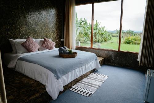 a bedroom with a bed and a large window at Loftpua ลอฟท์ปัว in Pua