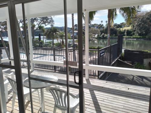 a porch with a table and chairs and a view of the water at Acacia Lodge Motel in Mangonui