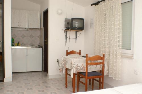 uma mesa de jantar com duas cadeiras e uma televisão na parede em Apartments with a parking space Pisak, Omis - 4281 em Mimice