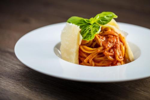 a white plate of spaghetti with a green leaf on top at Holiday Inn Rome - Eur Parco Dei Medici, an IHG Hotel in Rome