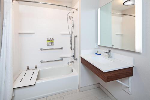 a bathroom with a sink and a tub and a mirror at Holiday Inn Express & Suites Clovis Fresno Area, an IHG Hotel in Clovis