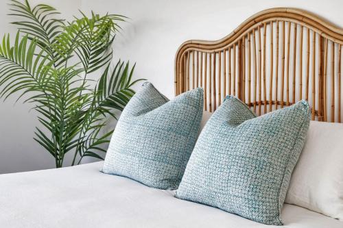 dos almohadas azules sentadas en una cama con una planta en Akuna Kiama, en Kiama