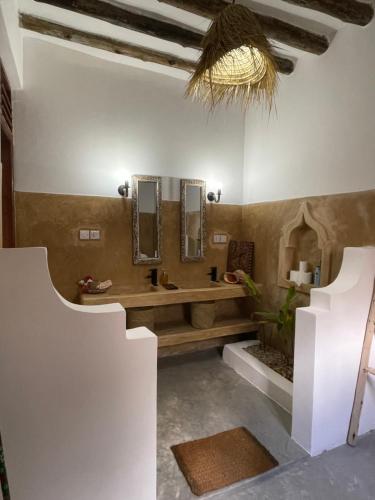 a bathroom with a sink and mirrors on the wall at Olamanga Beach Villa Adults Only in Jambiani