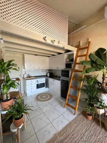 a kitchen with white cabinets and a ladder and plants at Boho style bungalow with ocean view in Mogán