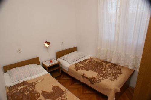 2 Betten in einem kleinen Zimmer mit Fenster in der Unterkunft Apartments by the sea Rogoznica - 4313 in Rogoznica