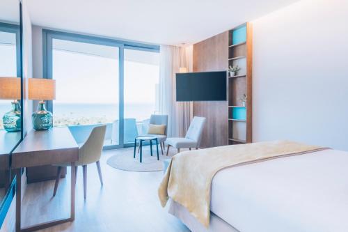 a bedroom with a bed and a desk and a dining room at Iberostar Selection Llaut Palma- Adults Only in Playa de Palma