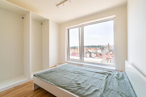 a bedroom with a bed and a large window at Penthouse # 81 with panoramic city view in Elite Rezidence with free parking in Prague