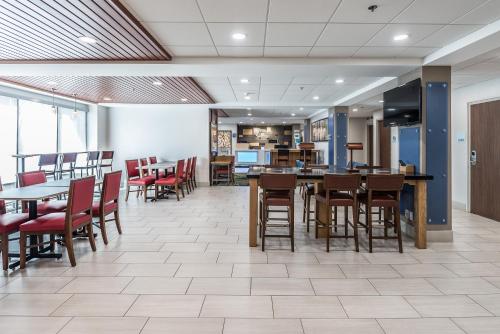 a dining area with tables and chairs in a cafeteria at Holiday Inn Express Flint-Campus Area, an IHG Hotel in Flint