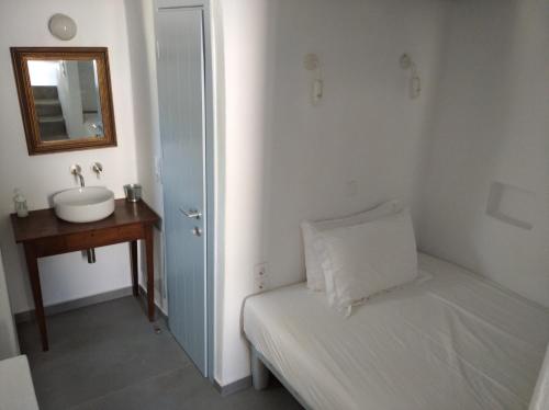a bathroom with a bed and a sink and a mirror at Theros Apartments Donoussa in Donoussa
