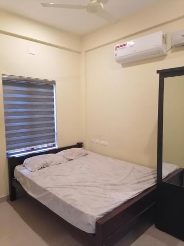 a small bedroom with a bed and a window at Queens Residency in Trichūr