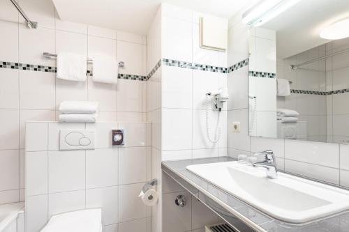 a bathroom with a sink, toilet and bathtub at acora Bochum Living the City in Bochum