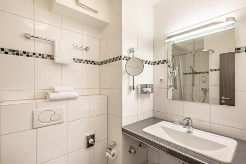 a white bathroom with a sink and a mirror at acora Bochum Living the City in Bochum
