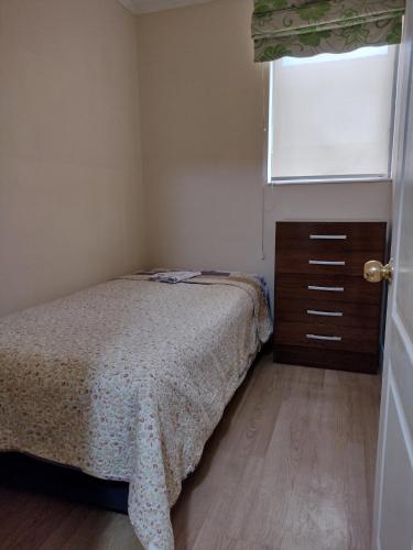 a bedroom with a bed and a dresser and a window at Puerto Perales Talcahuano in Talcahuano